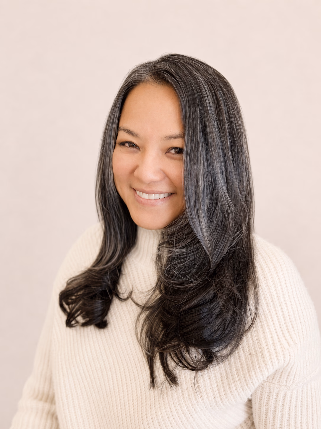 Natural grey blended through long dark hair so the grow-out stays soft.