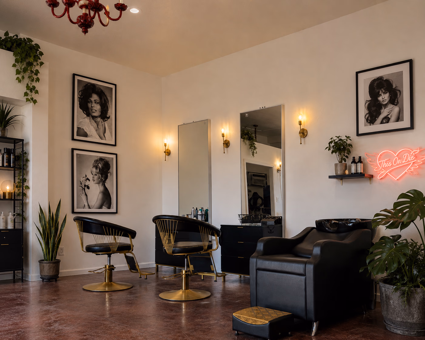 Inside This Or Die Salon — gold-legged chairs, mirrors, and the pink neon winged-heart sign.